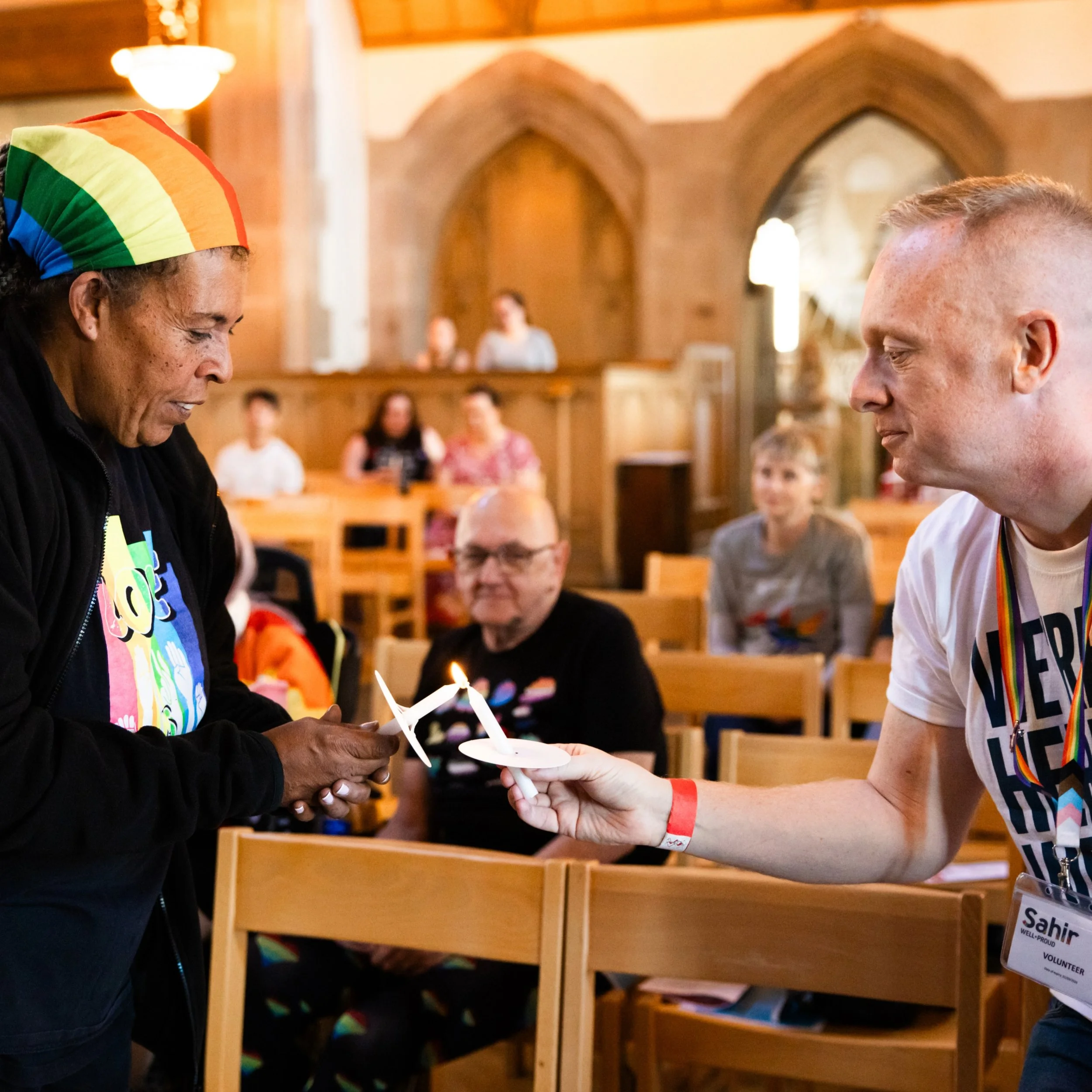 OTN trustee Sue Say (left) lights the candle of volunteer Mark Christopherson from Sahir, Liverpool City Region’s largest and oldest LGBTQ+ charity, at the Remember With Us vigil.